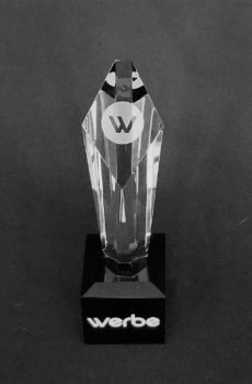 Faceted crystal tower award with an engraved logo on a black base